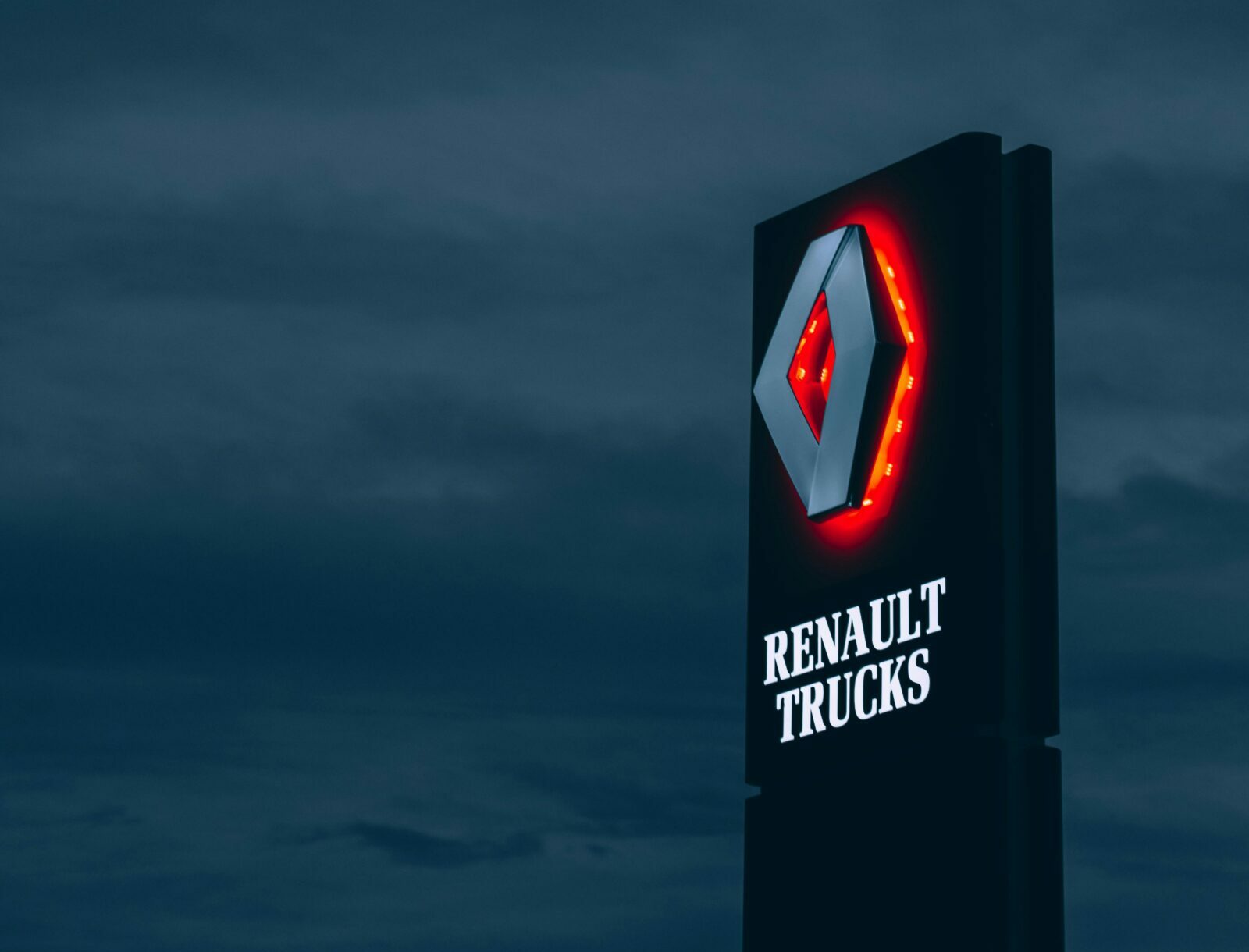 Black and red sign of Renault Trucks during the night.